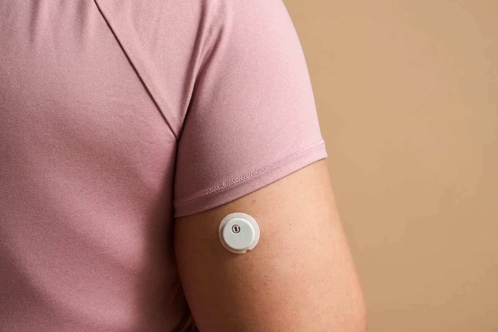 A person wears the round Libre glucose and ketone sensor on the back of their upper arm